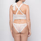 Back view of white lace corset lingerie with criss-cross straps and cheeky lace panties, ideal for anniversaries.