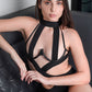 Woman in strappy black bodysuit lounging on sofa, edgy lingerie style perfect for boudoir and special occasions.