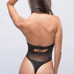 Rear view of a woman modeling a black thong teddy bodysuit with a starry mesh pattern and a chained choker neckline. Ideal for lingerie, boudoir, and intimate apparel.