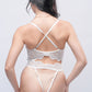 Back view of white lace teddy bodysuit featuring crisscross straps and cheeky thong cut.