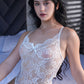 Seated pose of woman wearing white lace teddy bodysuit with delicate floral lace design.