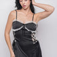 Woman posing in a black satin babydoll dress with lace trim and ribbon detail, front view.