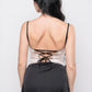 Back view of black satin babydoll dress with lace-up ribbon detail and lace hem.