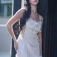 Woman posing outdoors in a white satin lace-trim babydoll dress, front view.