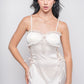 Woman in white satin babydoll dress with lace trim and ribbon bows, front view.