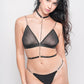 Black mesh lingerie with chain harness, bold clubwear or boudoir style.